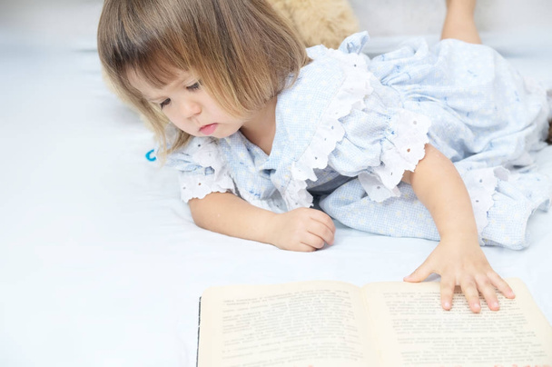 Little toddler girl refusing to read book and to learn looking unhappy - 写真・画像