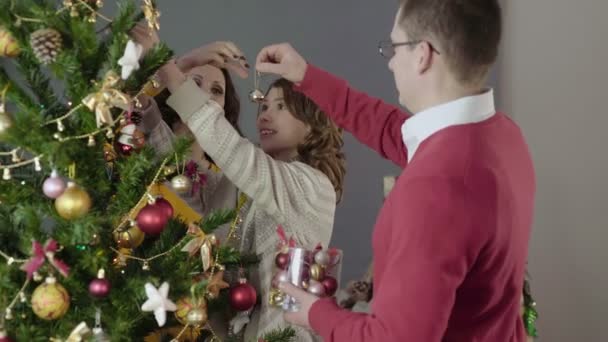 Ευτυχισμένη οικογένεια διακόσμηση του Χριστουγεννιάτικου δέντρου, προετοιμασία για τις διακοπές, γιορτινή διάθεση - Πλάνα, βίντεο
