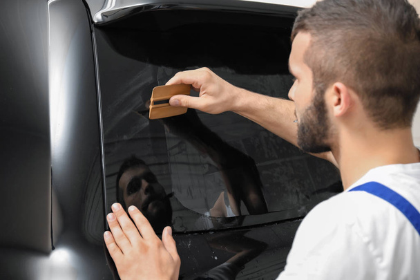 Worker tinting car window in shop - Photo, image