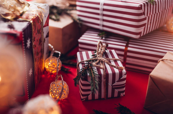 Geschenkboxen mit Tannenzweigen auf rotem Hintergrund dekoriert. - Foto, Bild