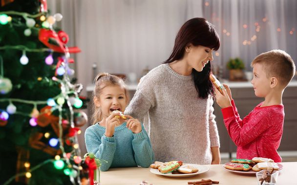 Family eating tasty Christmas cookies in kitchen - 写真・画像