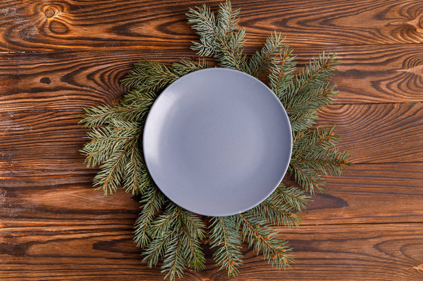 Plate empty on spruce branches on a brown background - Fotó, kép