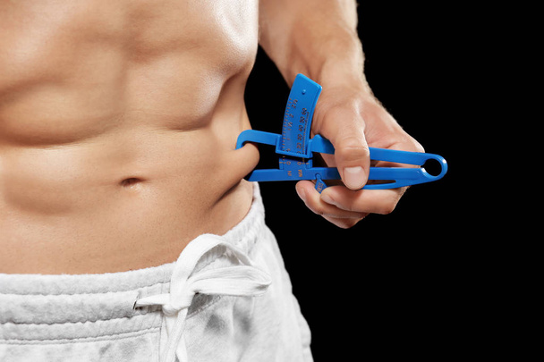 Muscular man measuring body fat - Фото, зображення