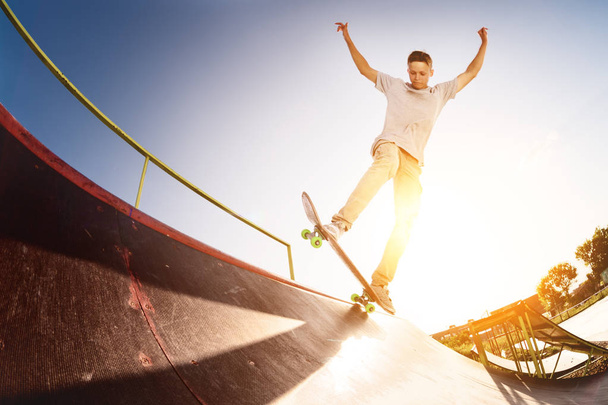 Teen skater hang up over a ramp on a skateboard in a skate park - Fotó, kép
