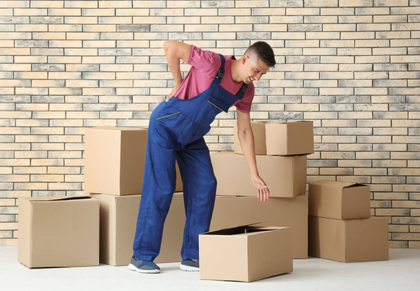 Man suffering from back ache while moving boxes, indoors - Photo, image
