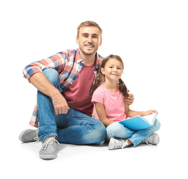 Young man and his little daughter reading book on white background - Photo, image
