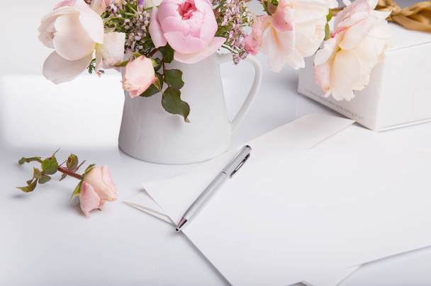 Tasainen lay laukaus kirjeen ja valkoinen kirjekuori valkoisella taustalla vaaleanpunainen englanti ruusu. Kutsukortit tai rakkauskirje. Äitien, Häät päivä, Naisten, Syntymäpäivä, Ystävänpäivä konsepti, ylhäältä
, - Valokuva, kuva