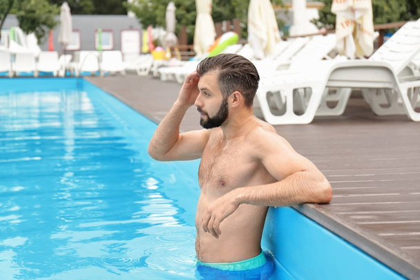 Handsome young man relaxing in blue swimming pool - Fotografie, Obrázek