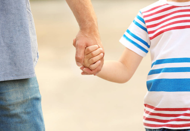 Boy holding father's hand outdoors - Zdjęcie, obraz