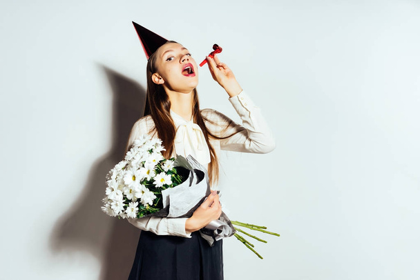 young beautiful girl celebrates something, in a red cap, holding a bouquet of white flowers in her hands - Photo, Image