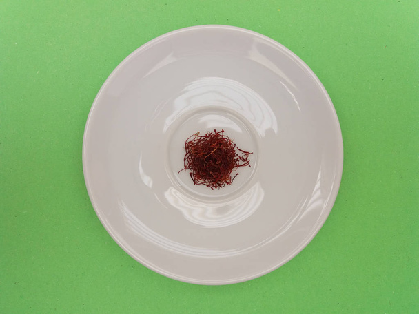 unground saffron in a white dish over green background - Photo, Image