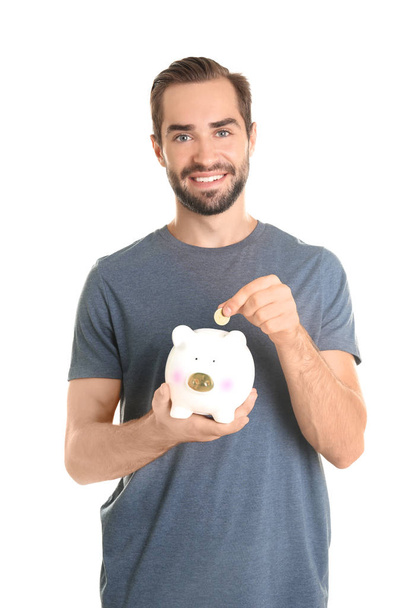 Young man with piggy bank on white background - Foto, Imagem