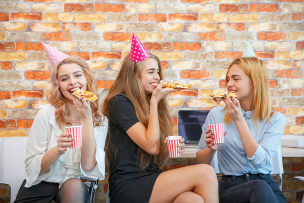 A company of three girls eating pizza at the office - Foto, Bild