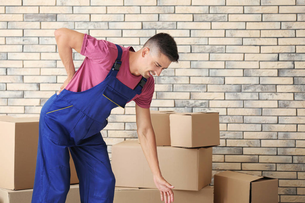 Man suffering from back ache while moving boxes, indoors - Foto, Bild