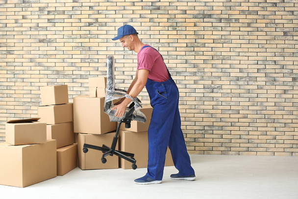 Delivery man holding chair, indoors - Foto, Bild