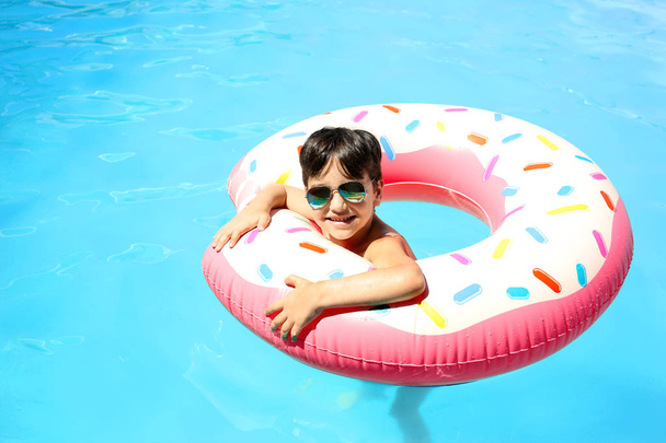 Cute little boy with inflatable donut in swimming pool - Foto, Bild