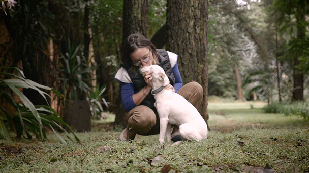 Mujer feliz dueño del perro besando a su mascota fuera en la naturaleza
 - Imágenes, Vídeo