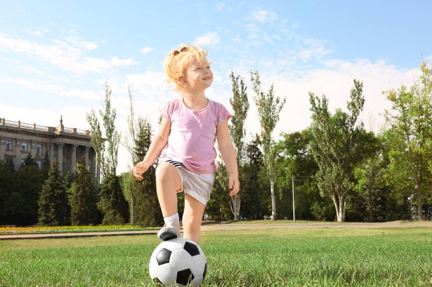Cute girl with soccer ball on lawn - Фото, зображення