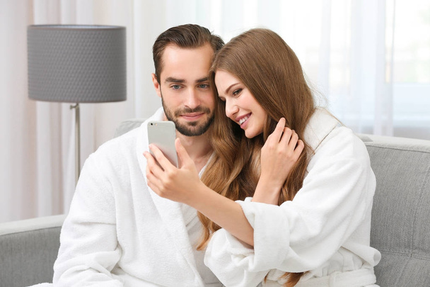 Young loving couple in bathrobes taking selfie at home - Foto, Imagem