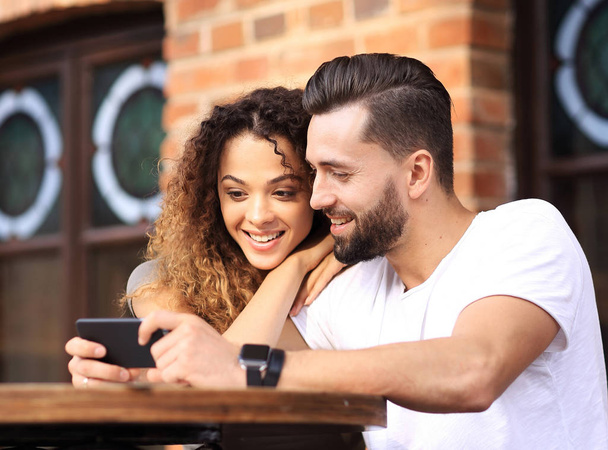 Happy loving  couple using a smartphone sitting in terrace - Foto, Imagem