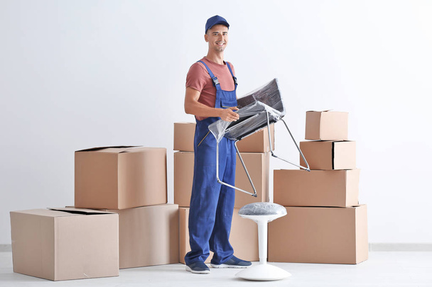 Delivery man holding chair, indoors - Foto, Imagem