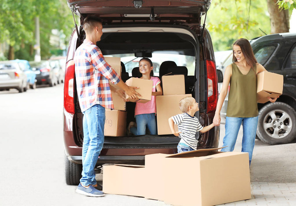 Happy family with boxes near car, outdoors - Photo, Image