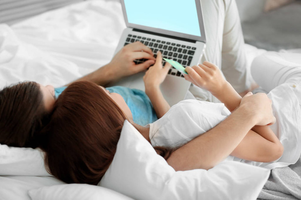 Evde yatakta yatarken dizüstü bilgisayar ile genç çift. Internet alışveriş kavramı - Fotoğraf, Görsel