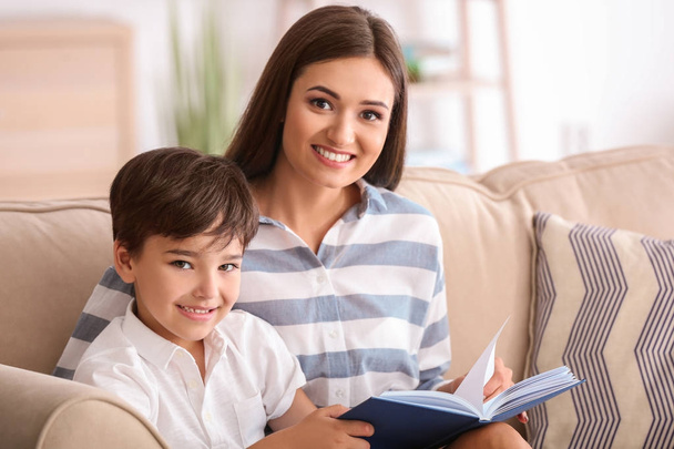 Young woman and her little son reading book at home - Foto, imagen