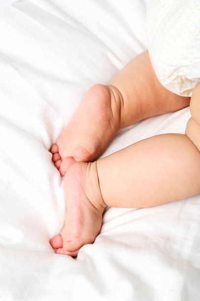 Newborn baby feets on white bed - Fotoğraf, Görsel