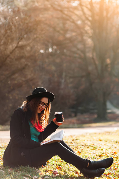 Mujer joven con libro y café en el parque
 - Foto, Imagen