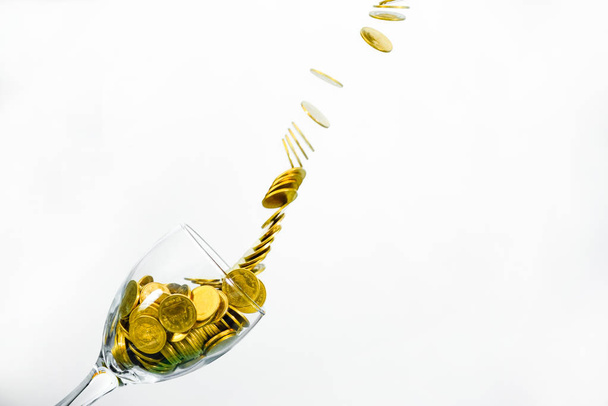 Goldmünzen plätschern in einem Glas Champagner auf der Wandrückwand - Foto, Bild