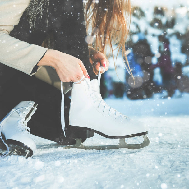 Woman tie shoelaces figure skates at ice rink close-up - Fotó, kép