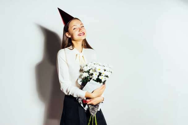 happy girl in festive cap holding bouquet of flowers - Foto, Imagen