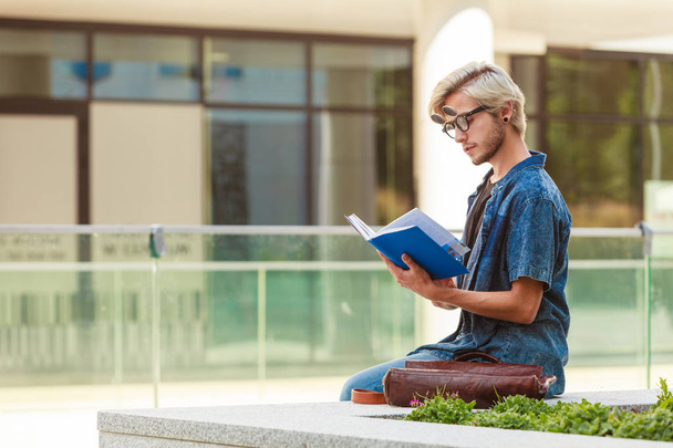 Hipster guy holding notebook sitting on ledge - Fotoğraf, Görsel