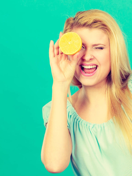 Girl covering her eye with lemon citrus fruit - Valokuva, kuva