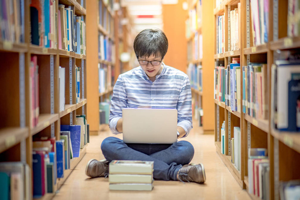 Jovem asiático estudante usando laptop na biblioteca
 - Foto, Imagem
