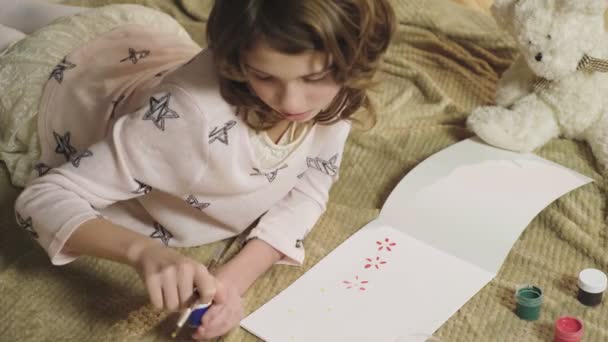 Little girl drawing colorful flowers in her album, dreaming of summer and warmth - 映像、動画