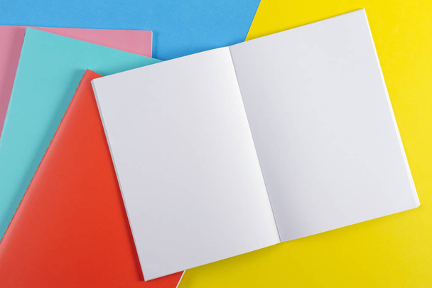 Ανοίξτε το σημειωματάριο και πολύχρωμο σημειωματάρια σε μπλε και κίτρινο φόντο - Φωτογραφία, εικόνα