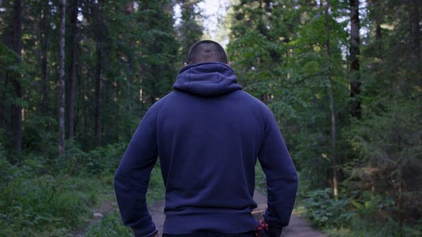 Person in a hood standing. Man in the hood in the woods. Sport in the forest on the nature - Foto, Bild