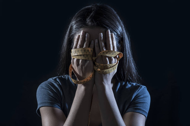 Anoreksiya veya bulimia beslenme bozukluğu muzdarip, depresif ve endişeli genç kızın yüzü kapsayan terzi ölçü bant sarılmış eller - Fotoğraf, Görsel