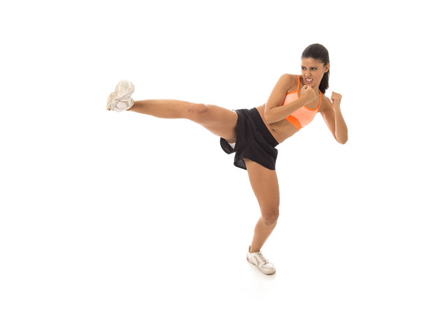 joven atractivo y furioso latina deporte mujer en lucha y patada boxeo entrenamiento entrenamiento lanzando ataque de patada agresiva
 - Foto, imagen