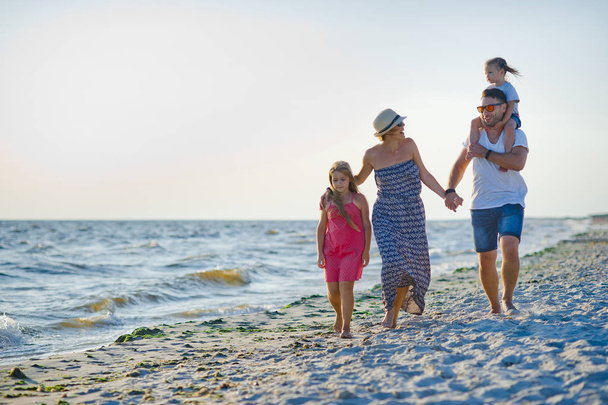 Счастливая семья гуляет по морю, держа за руки
. - Фото, изображение
