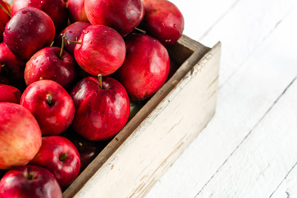Red apples on table in wooden crate, pile of fresh apple on white background - Photo, Image