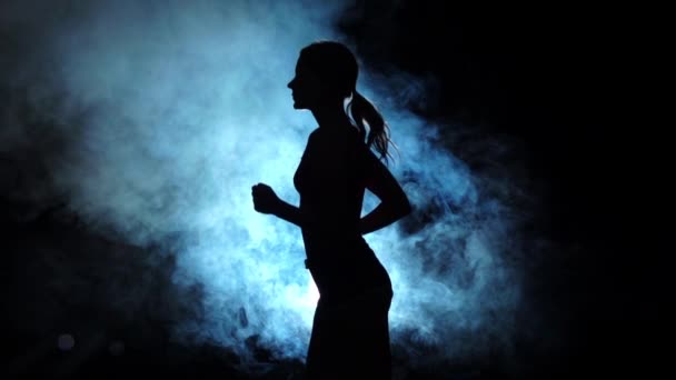 Κυρία τρέχει σε ένα καπνιστή επίκεντρο σε μαύρο φόντο. Σιλουέτα. Αργή κίνηση - Πλάνα, βίντεο