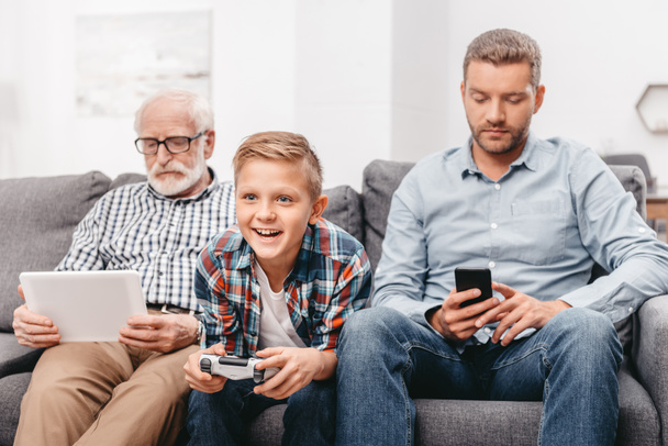 Family sitting on couch with devices - Foto, imagen