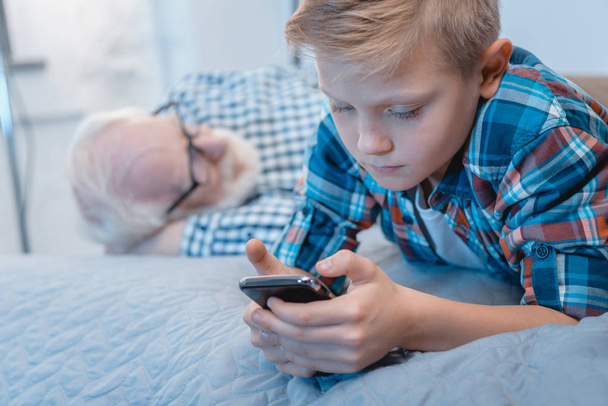 Little boy using smartphone on bed - Photo, Image