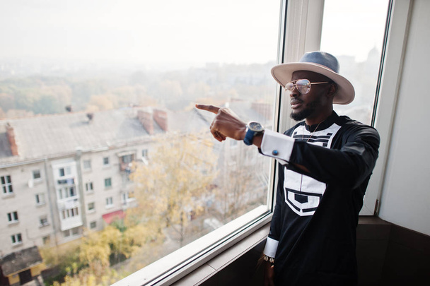 Rich african man looking at panoramic window at his penthouse. P - Φωτογραφία, εικόνα
