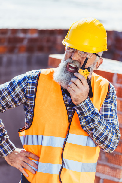 Trabajador de la construcción hablando por radio portátil
 - Foto, Imagen