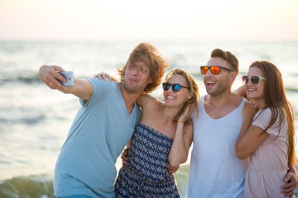 Ομάδα χαρούμενα νέων ανθρώπων που φωτογραφήθηκε στην παραλία. - Φωτογραφία, εικόνα
