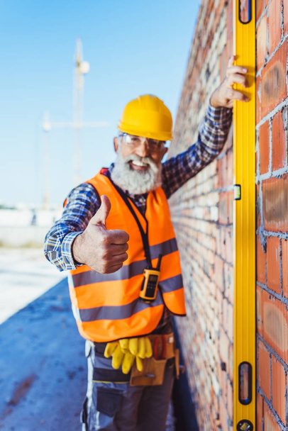 worker with spirit level showing thumb up - Photo, Image